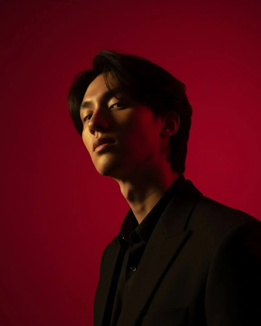Portrait of Zin Paing Soe in a black suit against a crimson backdrop